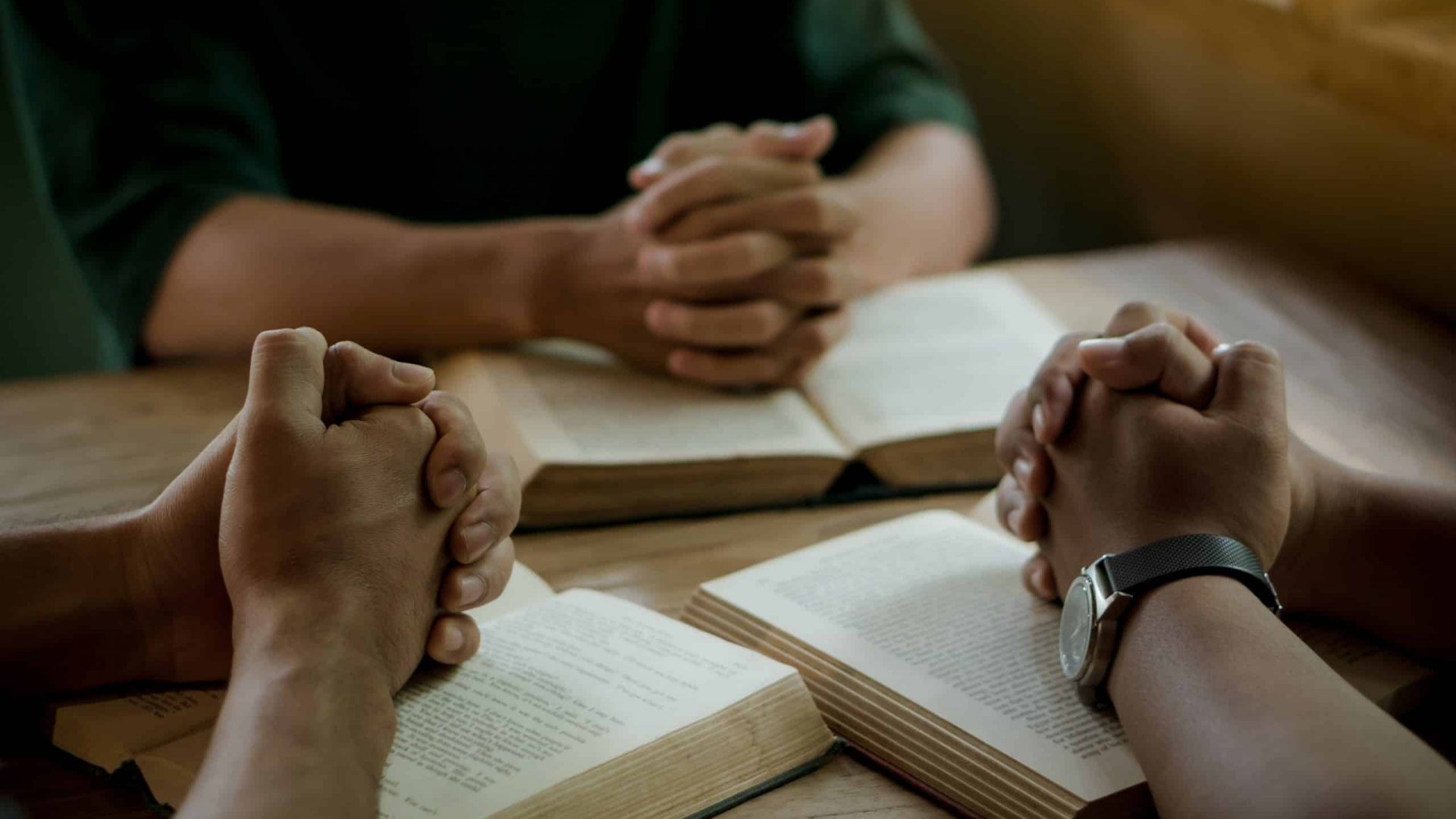 Group of christian people reading and study bible in home and pray together.Group of people holding hands praying worship god.Diverse religious shoot.